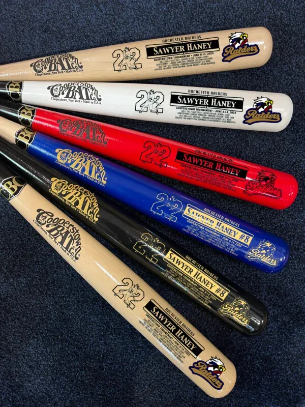 Colorful personalized baseball bats displayed on carpet.